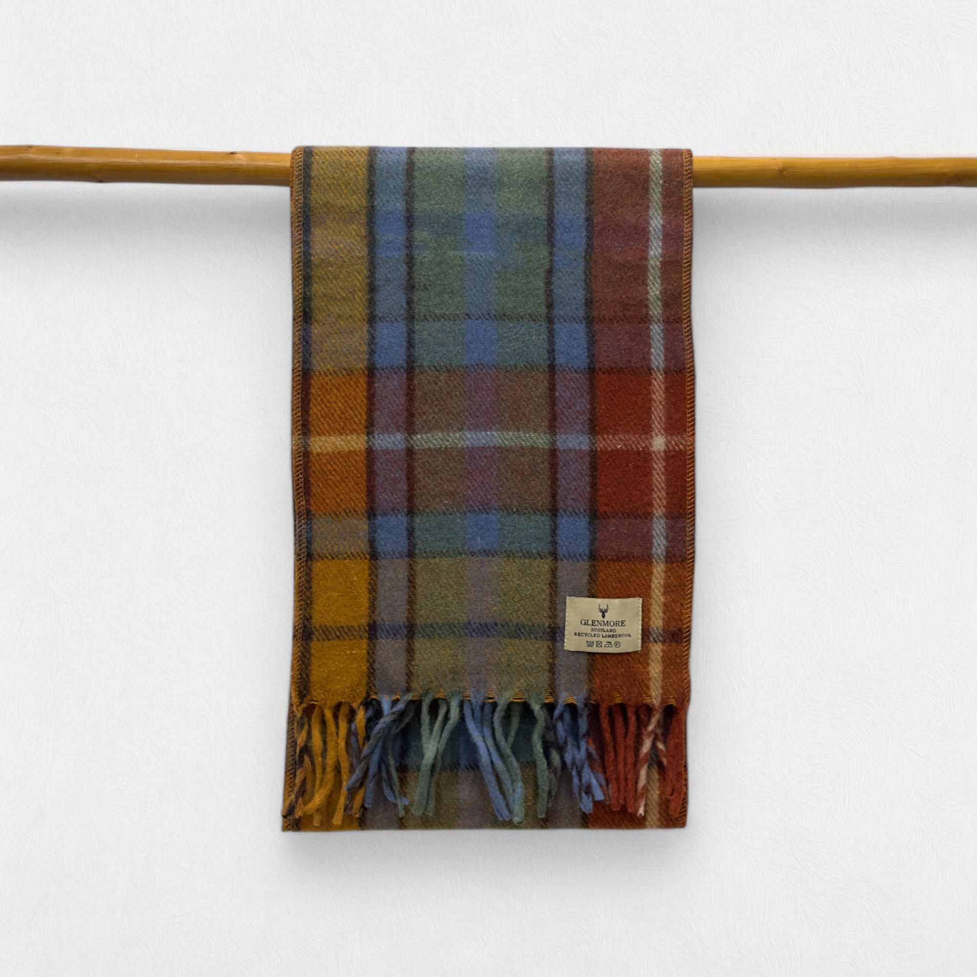 A antique buchanan scarf with fringes, displayed on a wooden rod against a white background.