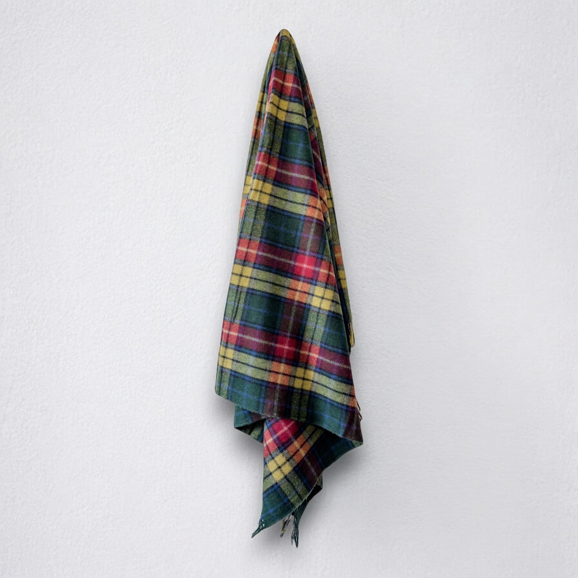 a 100% recycled blanket in modern buchanan tartan hanging from a wall hook on a white background 