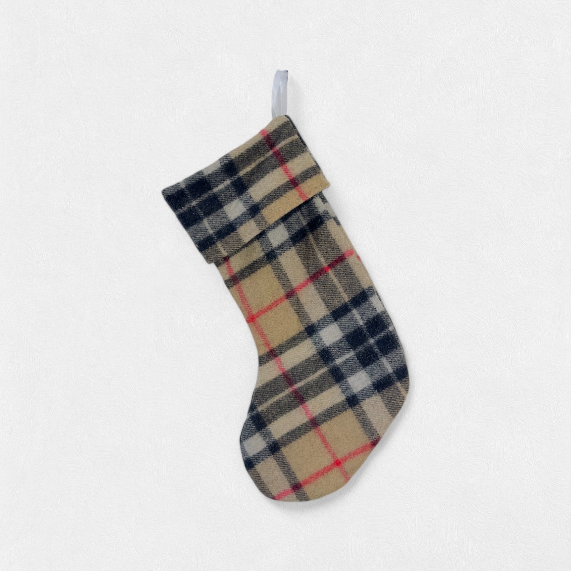 The Camel Thomson 100% wool Christmas Stocking hanging from a hook on a white background.