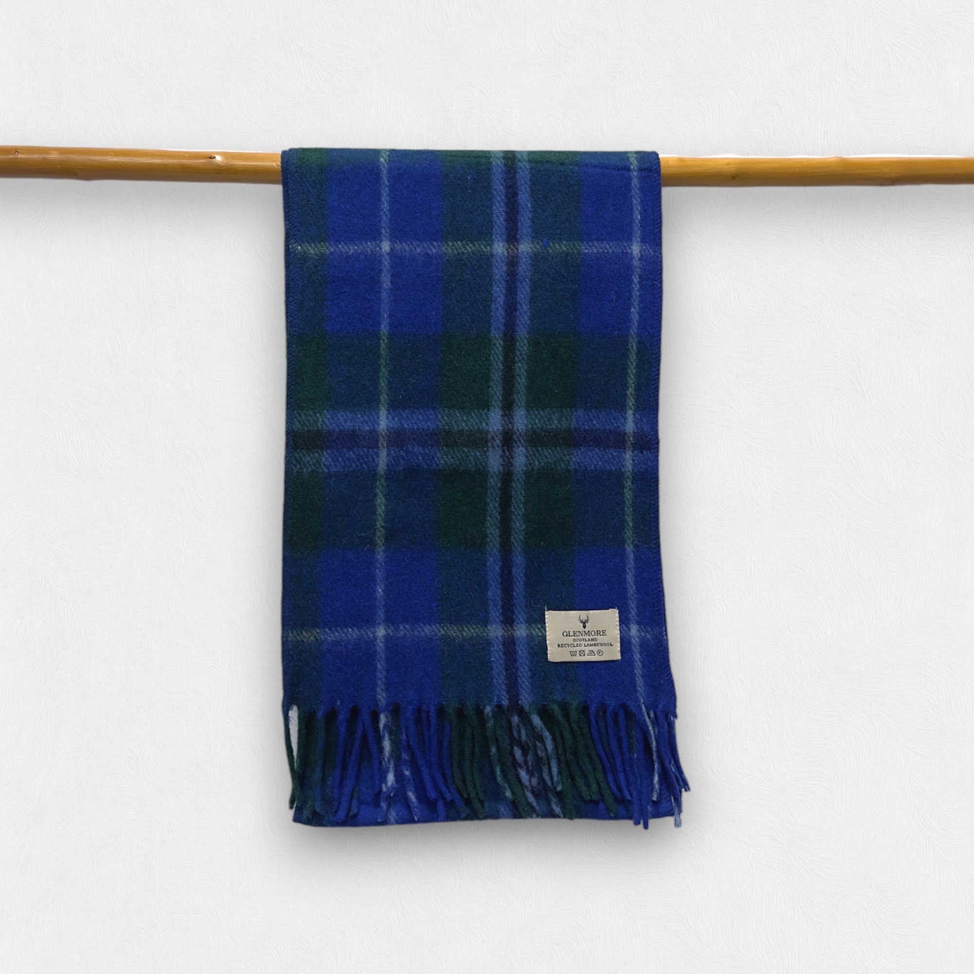 A douglas tartan checkered scarf with fringes displayed on a wooden rod.
