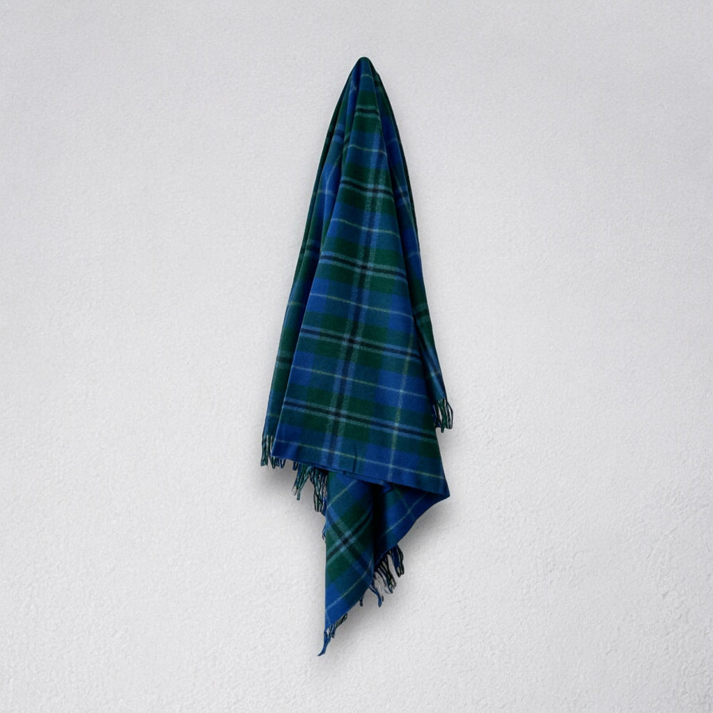a 100% recycled blanket in douglas tartan hanging from a wall hook on a white background 