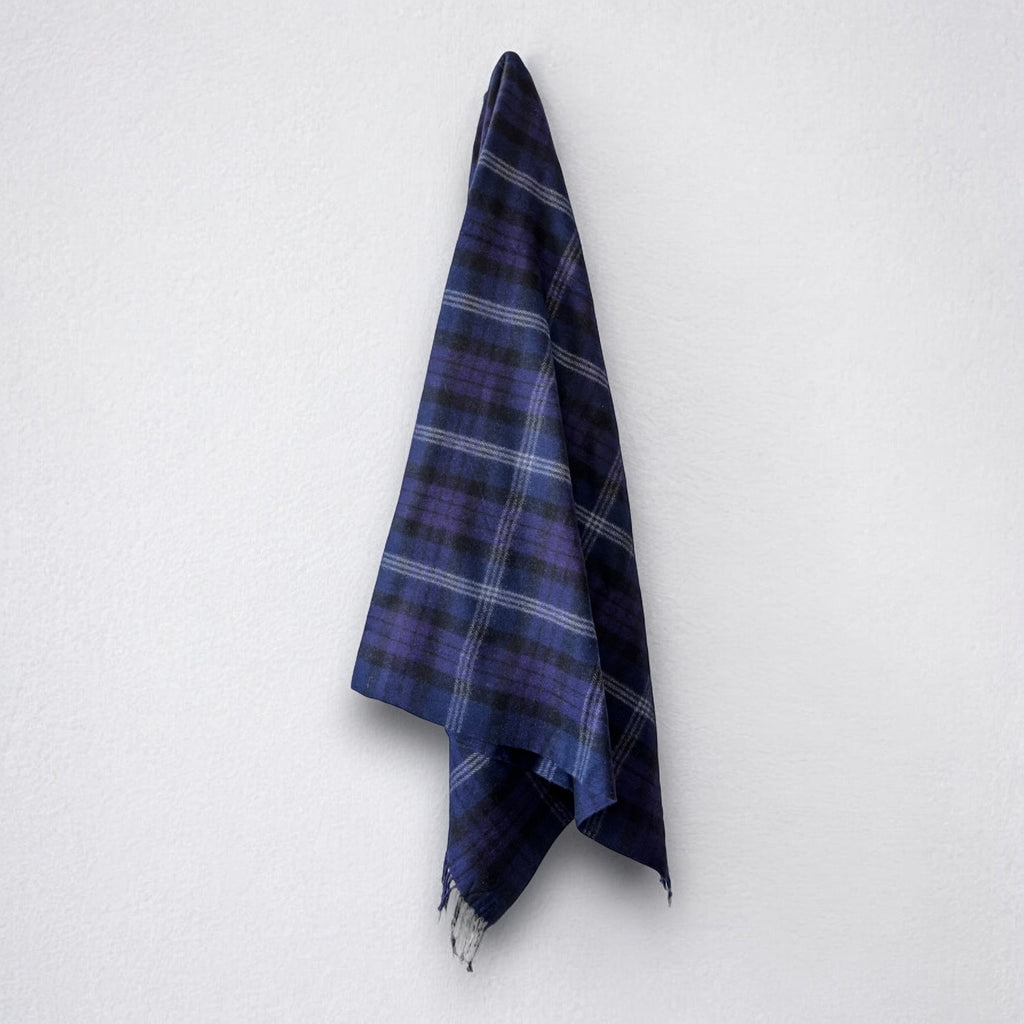 a 100% recycled blanket in scottish heritage tartan hanging from a wall hook on a white background 