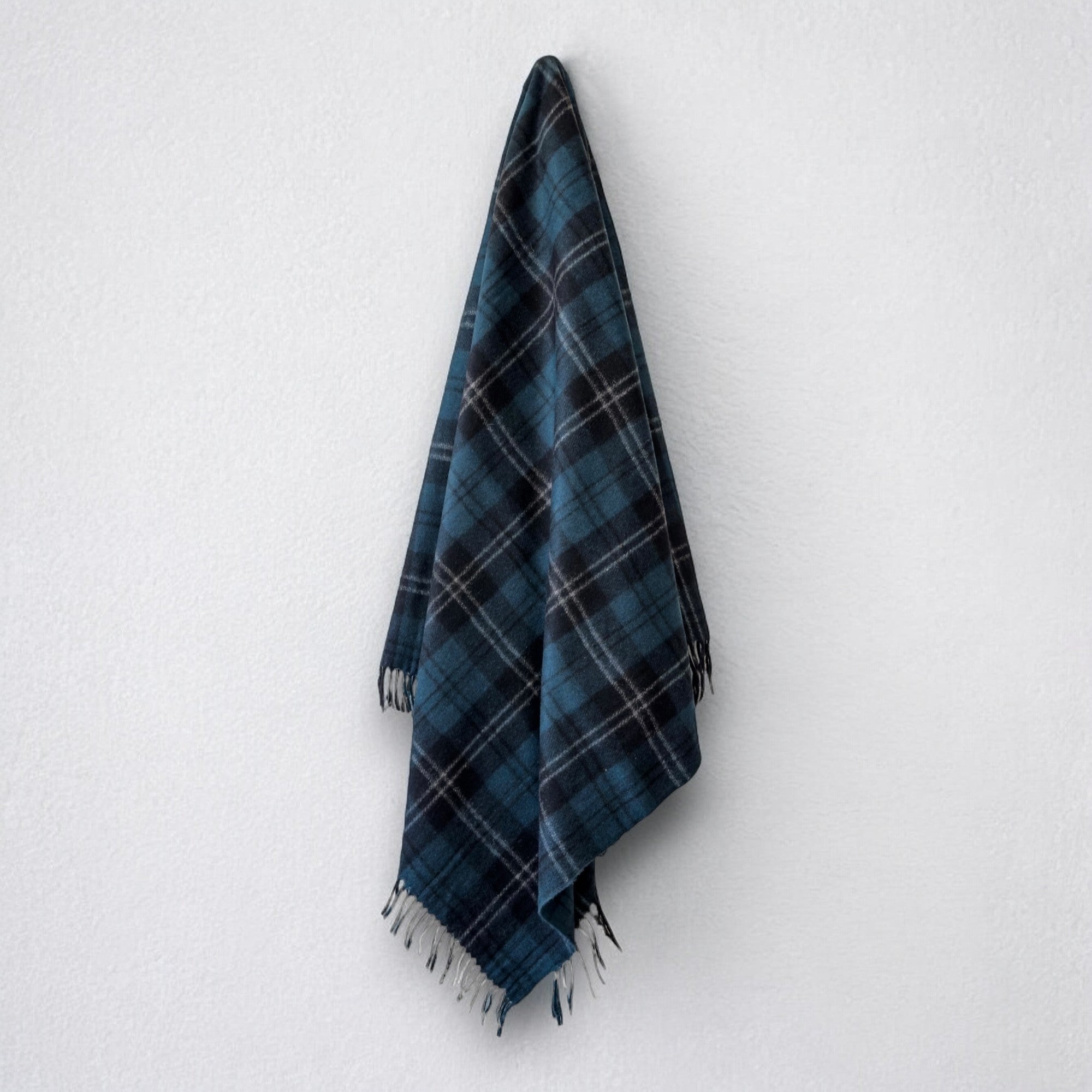 a 100% recycled blanket in ramsay blue tartan hanging from a wall hook on a white background 