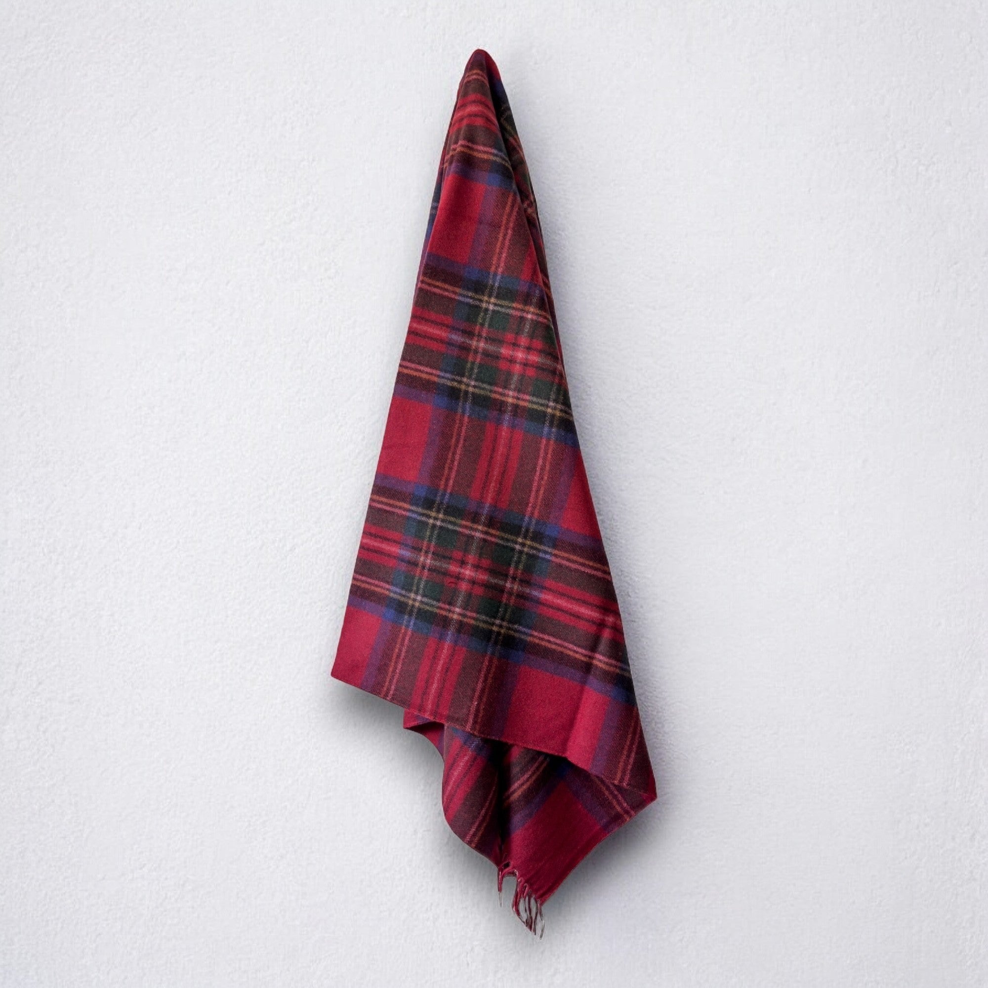 a 100% recycled blanket in royal stewart tartan hanging from a wall hook on a white background 