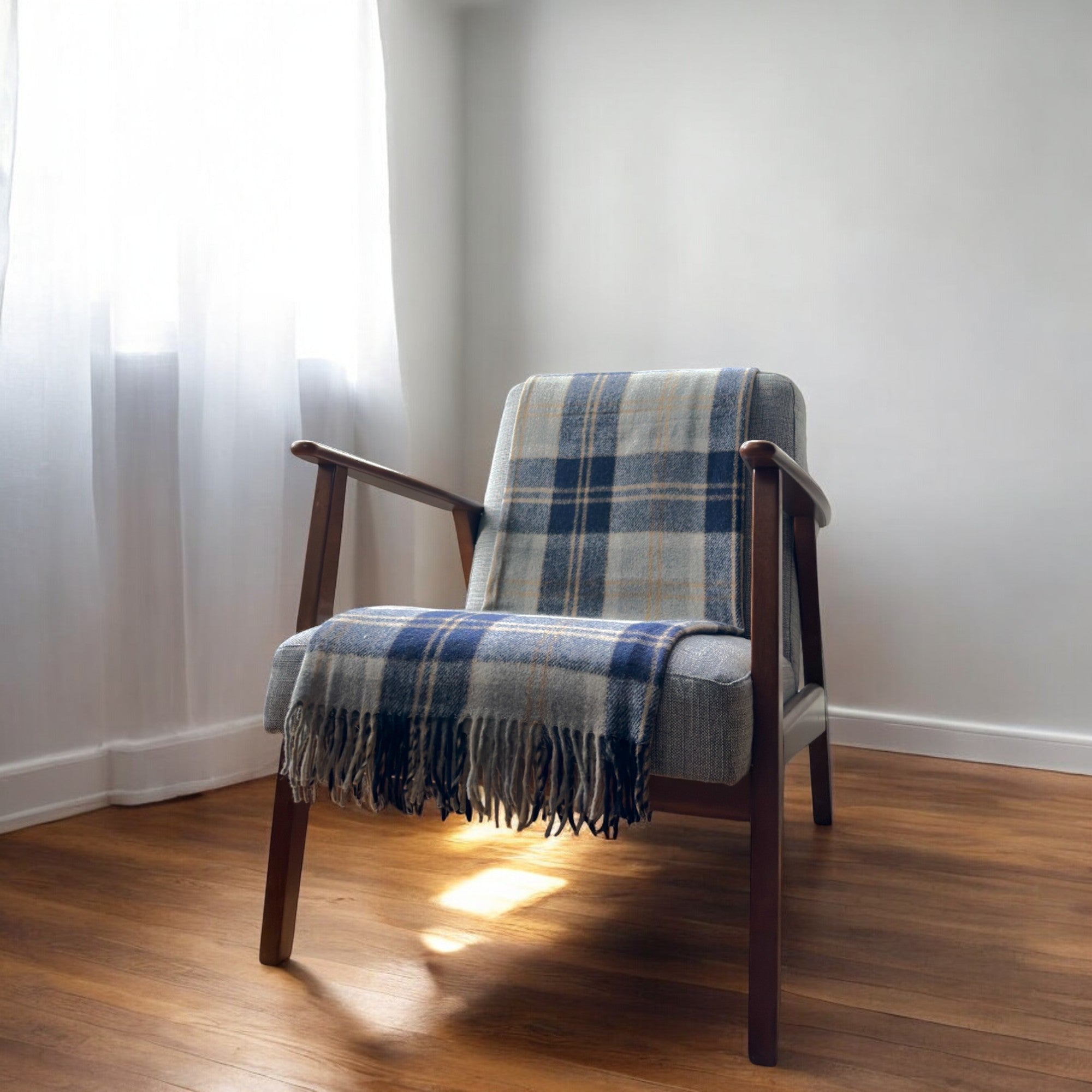 a 100% recycled blanket in silver bannockbane tartan draped over a chair in a cosy room