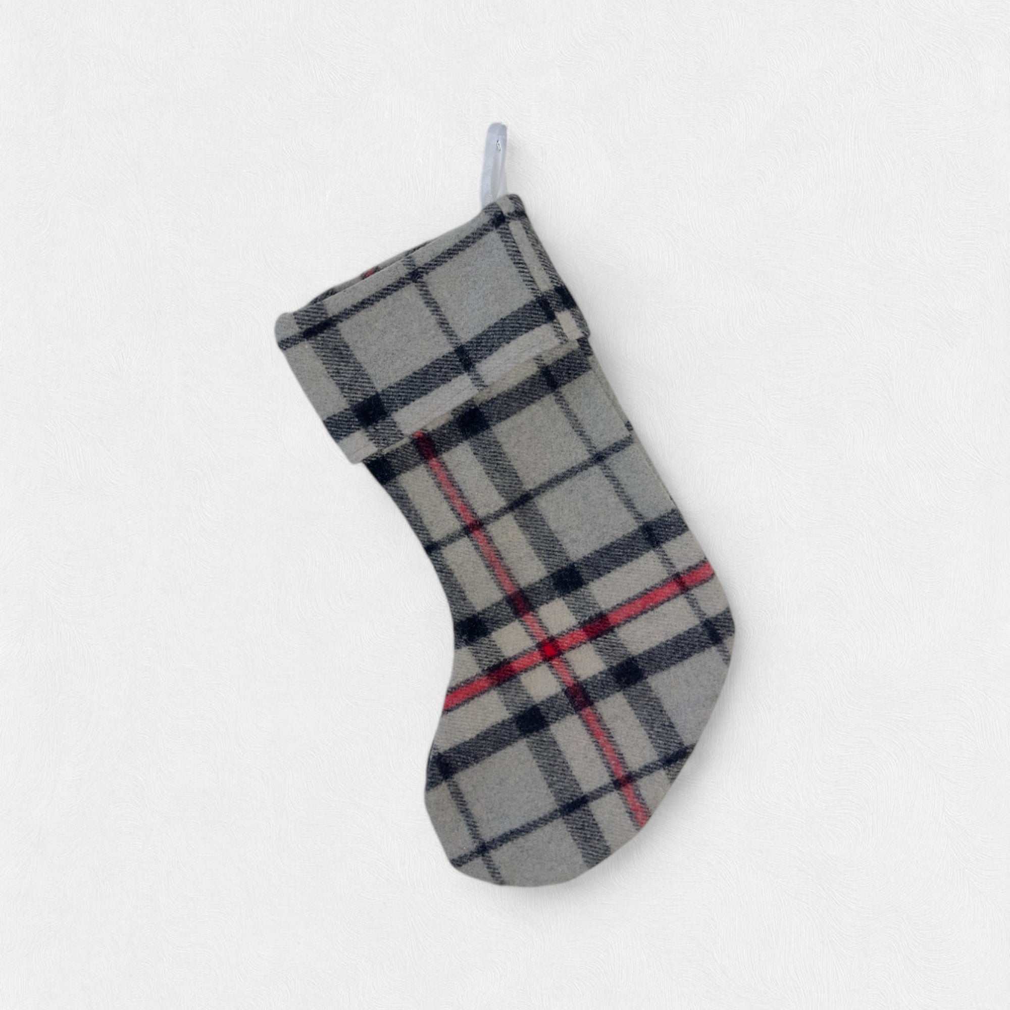 The Thomson Grey 100% wool Christmas Stocking hanging. from a hook with a white background.