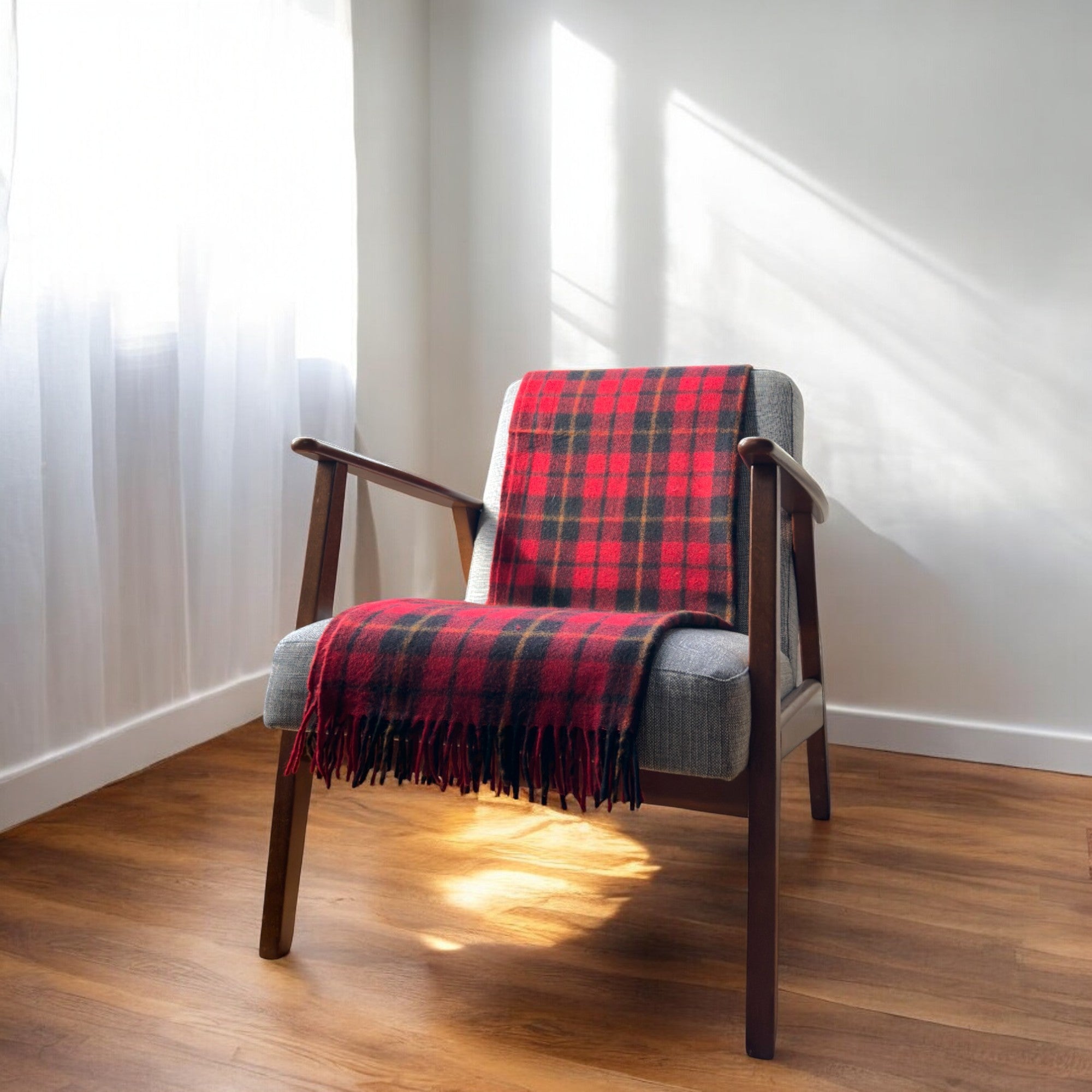 a 100% recycled blanket in wallace tartan draped over a chair in a cosy room