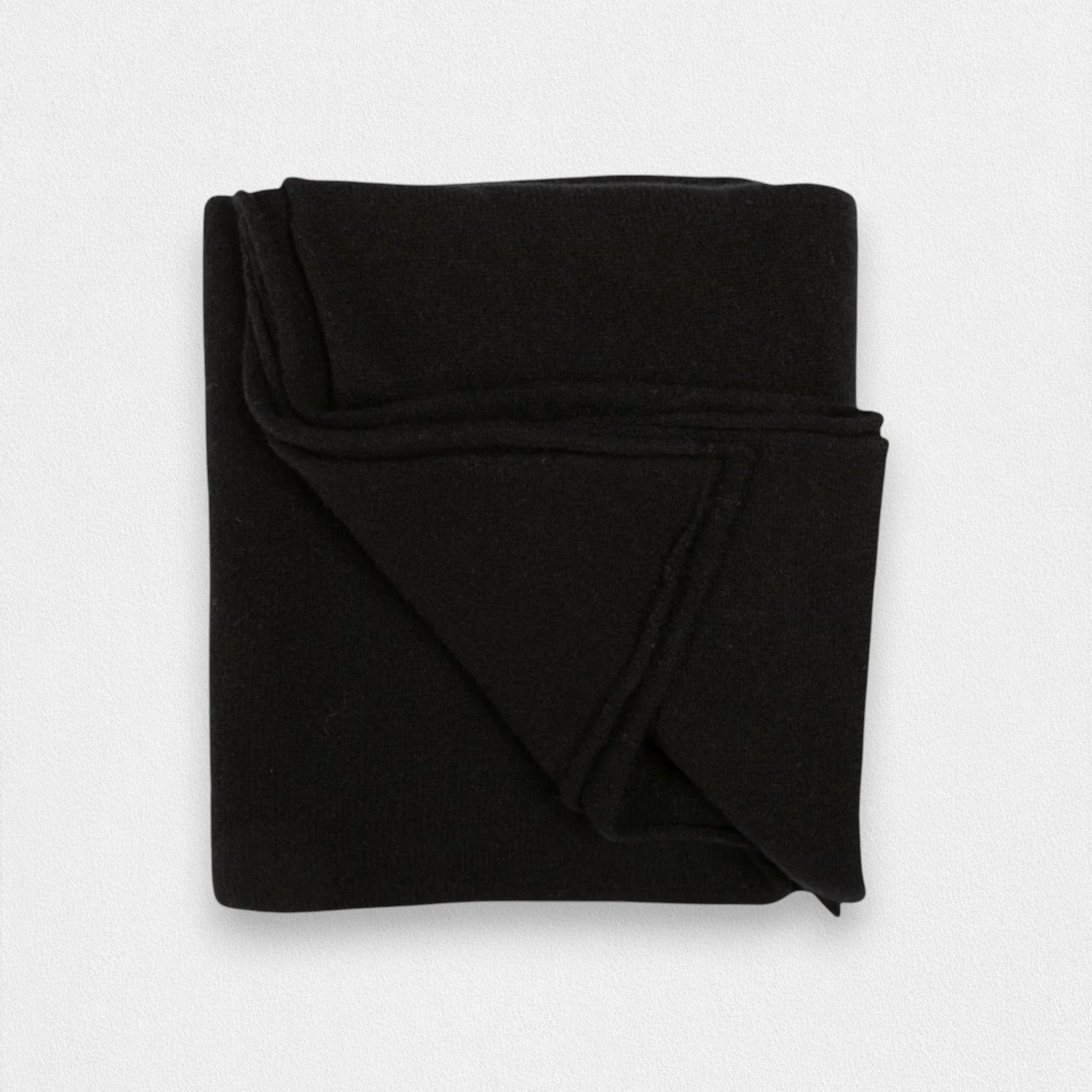 A folded black cashmere wrap on a plain background.