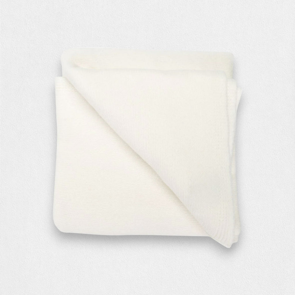 A folded white cashmere blanket on a plain background.