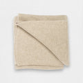 A natural cream colored 100% cashmere blanket folded neatly.